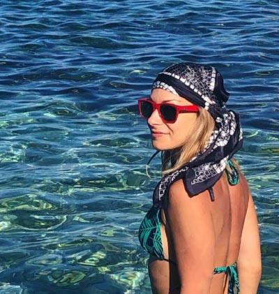 17 woman wearing a cool graphic silk scarf around the head at the beach with a bikini